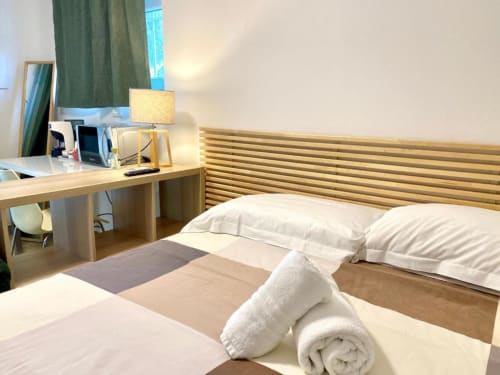 Modern single room at The Green Gate Airport Guest House in Pisa with wooden headboard, desk, lamp, and white towels on bed