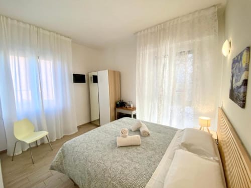 Camera matrimoniale luminosa al Green Gate di Pisa con vista sul giardino, letto confortevole, armadio e tende trasparenti