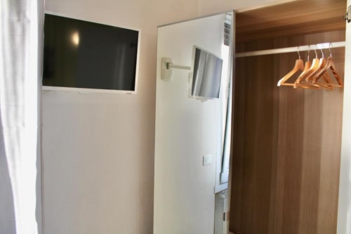 Camera moderna alla Green Gate Airport Guest House di Pisa con TV a schermo piatto, armadio in legno con appendiabiti e biancheria bianca