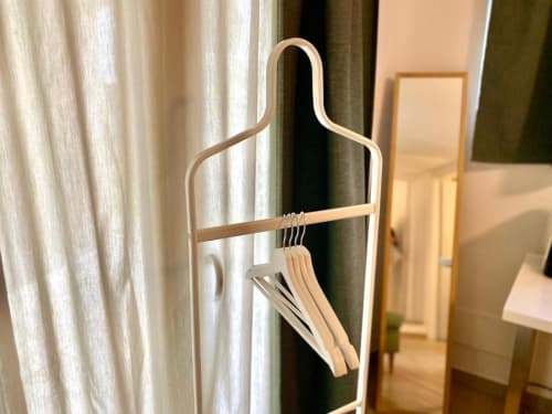 Wooden coat stand with hanging hangers in hotel room at The Green Gate, Pisa guest house