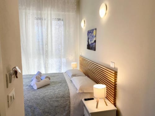 Modernes Schlafzimmer im The Green Gate Pisa mit Holzkopfteil, weißer Bettwäsche, Nachttischlampen, Wandleuchten und Gartenblick