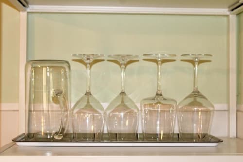 Clear glassware display in hotel room: pitcher and stemmed glasses on shelf at The Green Gate in Pisa