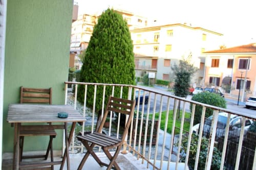 Balcone privato con sedia e tavolo in legno con vista sul giardino di The Green Gate guest house a Pisa, Italia