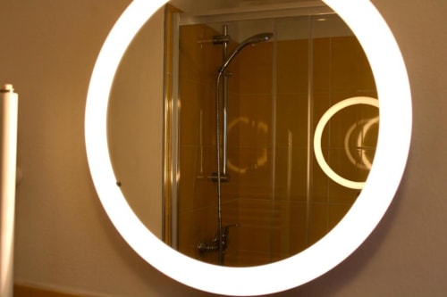 Modern circular LED-lit mirror in bathroom at The Green Gate Airport Guest House, Pisa hotel room