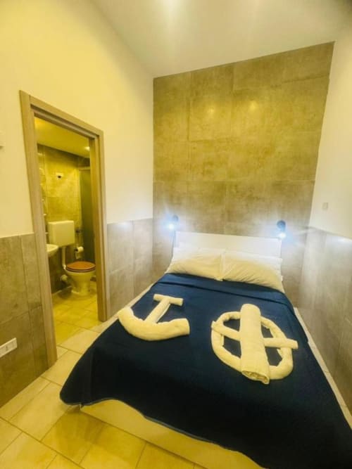 Compact bedroom at Neapolis Tecnotourist with single bed, yellow and black decor, ensuite bathroom, and tiled walls in