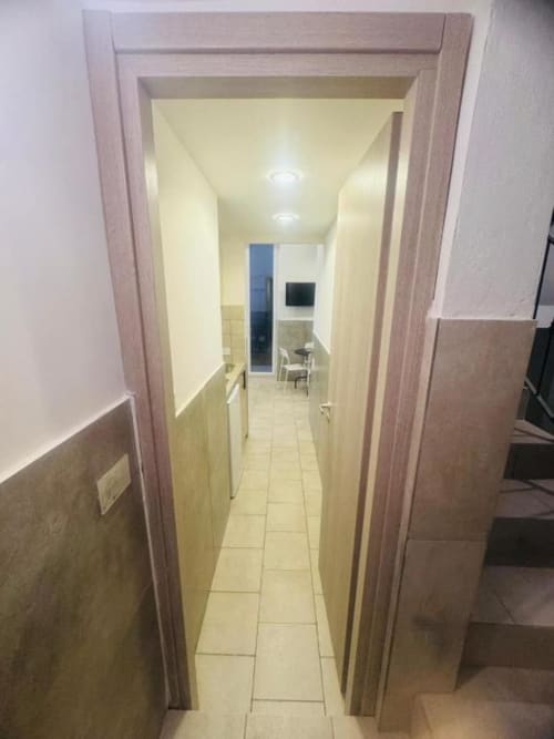 Narrow hallway leading to kitchen area at Neapolis Tecnotourist apartment with tile flooring and warm lighting
