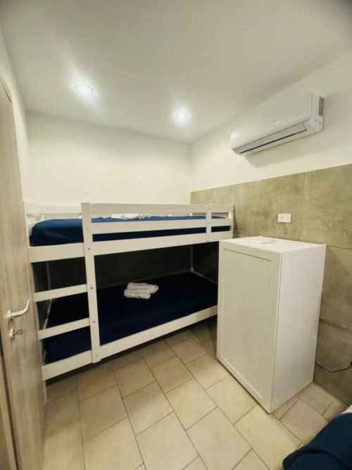 Modern bedroom with white and black bunk beds, white refrigerator, tiled floor, air conditioning unit, and recessed lighting