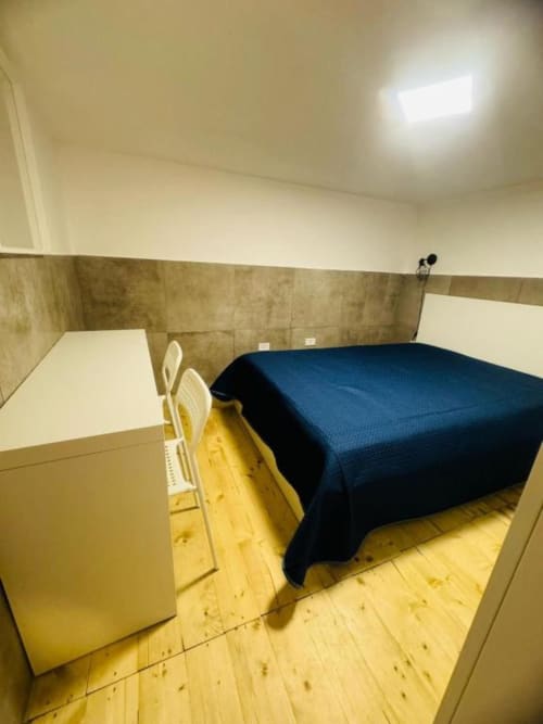 Spacious bedroom in Neapolis Tecnotourist apartment featuring double bed with blue cover, wooden flooring, and modern