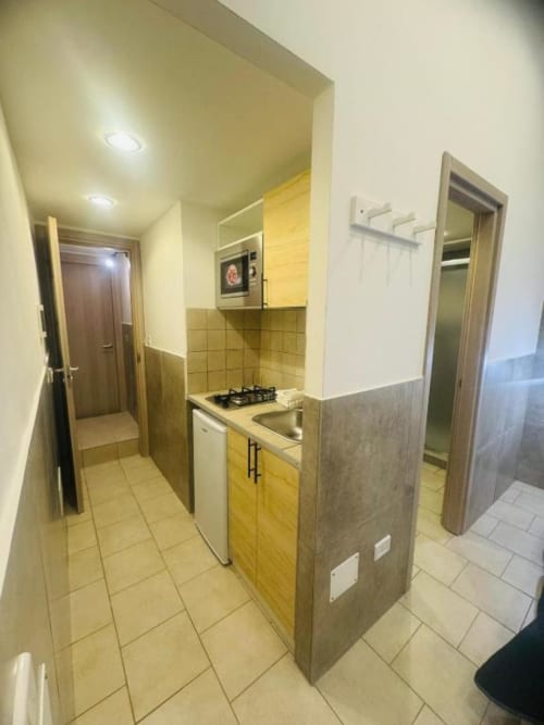 Modern kitchen in One-Bedroom Apartment at Neapolis Tecnotourist with yellow cabinets, gas hob, sink and tiled flooring