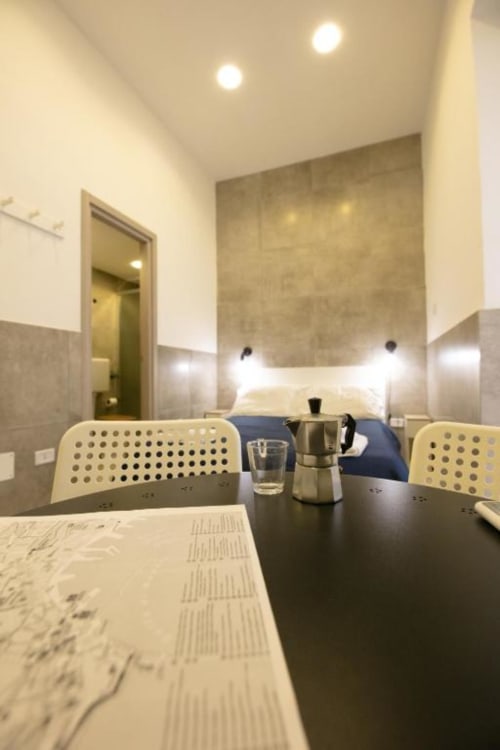 Modern one-bedroom apartment at Neapolis Tecnotourist with dining table, kitchen area, and bedroom view in Naples, Italy