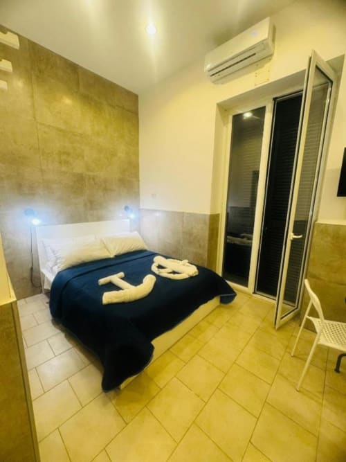 Cozy bedroom at Neapolis Tecnotourist with double bed, dark blue bedding, yellow tile flooring, air conditioning, and