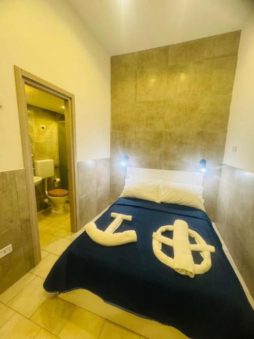 Compact bedroom at Neapolis Tecnotourist B&B with single bed, en-suite bathroom, yellow tile walls, and dark bedding