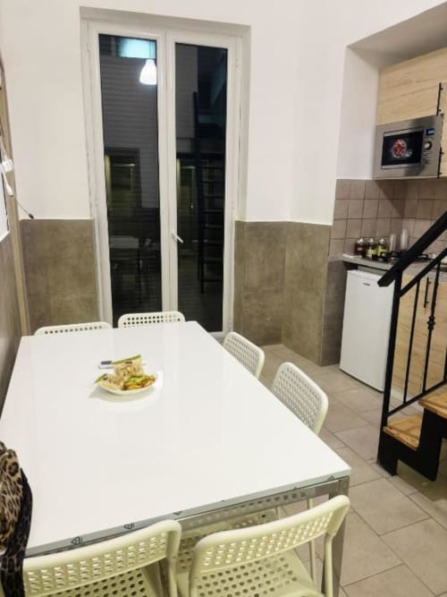 Moderna zona cucina-pranzo con tavolo bianco, sedie e elettrodomestici all'appartamento Neapolis Tecnotourist in Italia