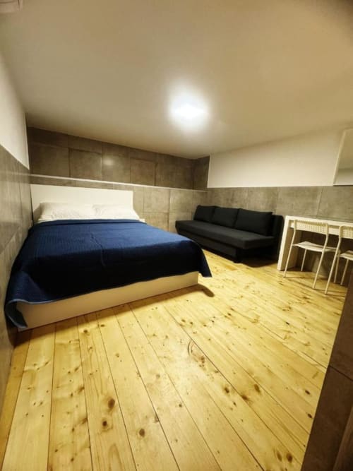 Spacious bedroom at Neapolis Tecnotourist BnB with bed, sofa, wooden floors, and modern amenities