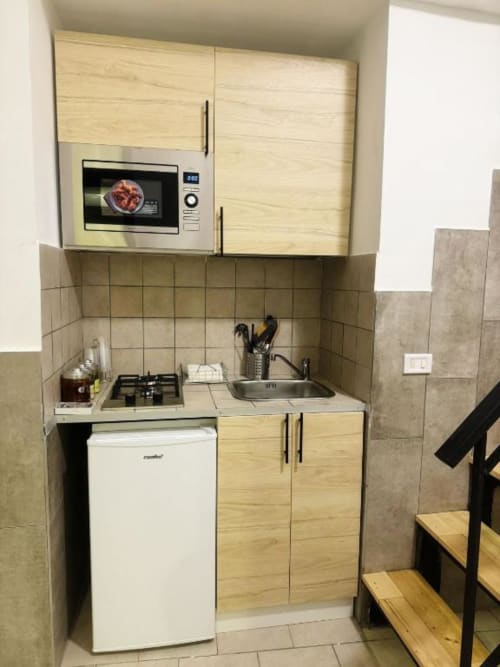 Angolo cottura compatto nell'appartamento di Neapolis con microonde, piano cottura, lavello, frigorifero e mobili in legno