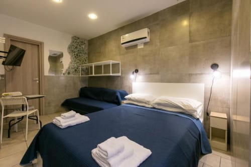 Modern ground floor apartment bedroom at Neapolis Tecnotourist with blue bed, white pillows, air conditioning, and tile