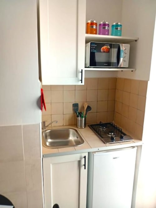 Compact kitchenette in Neapolis Tecnotourist BnB with sink, gas stovetop, microwave, and storage at Italian hotel
