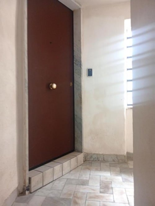 Modern hallway with dark red door and tile flooring in Neapolis Tecnotourist double room with kitchen