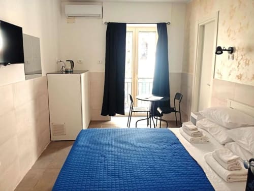 Neapolis Tecnotourist double room with blue bed, balcony, TV, and city view in Italy
