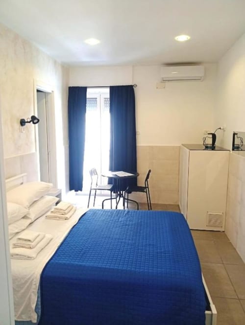 Neapolis Tecnotourist double room with blue bedcover, balcony with city view, and modern amenities