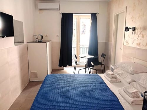 Neapolis Tecnotourist double room with blue bed, TV, balcony access, refrigerator, and city views in Naples