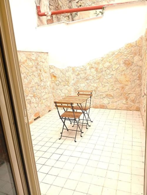 Private terrace at Neapolis Tecnotourist with wooden table and chairs, stone walls, and city view in Naples, Italy