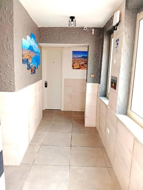 Modern hallway at Neapolis Tecnotourist BnB with tiled flooring, textured walls, cityscape artwork, and room access doors in