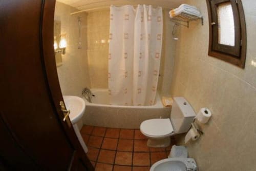 Baño de la habitación doble del Hotel Llibrada con ducha, aseo, bidé y suelo de terracota en Benasque