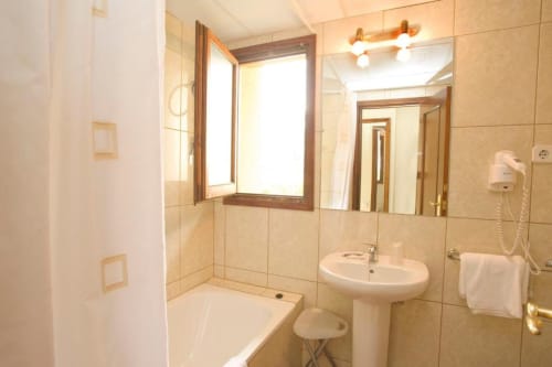Cuarto de baño moderno con azulejos beige, lavabo de pedestal, espejo y ducha en habitación doble del Hotel Llibrada, Benasque