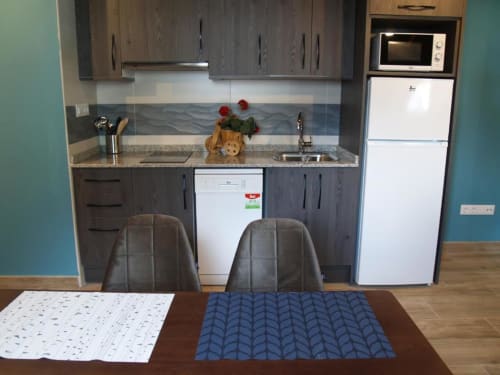 Cocina moderna en Benasque con mesa de comedor, muebles oscuros, electrodomésticos blancos y pared de acento turquesa.