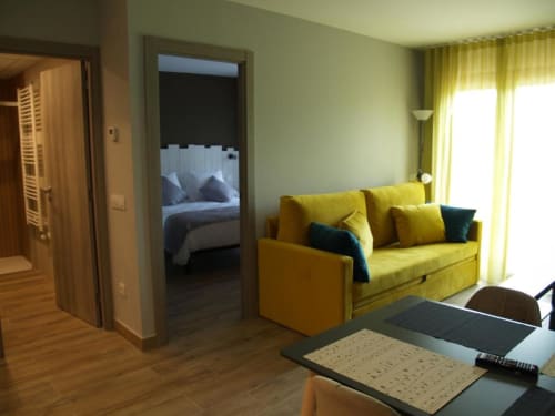 Sofá amarillo en la sala de estar moderna del Hotel Llibrada en Benasque, con vistas a la montaña y acceso a la terraza
