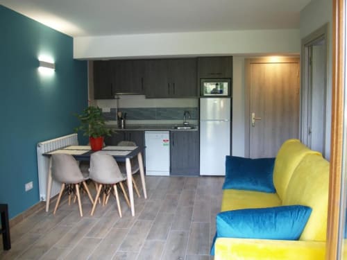 Interior moderno de apartamento en Benasque con comedor, cocina y sofá amarillo y azul colorido