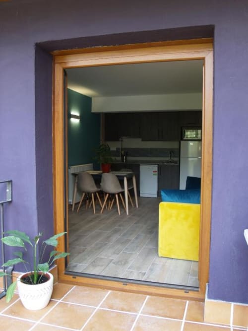 Moderna cocina y comedor de aparthotel con marco de madera, pared de acento verde azulado y caja de almacenamiento amarilla