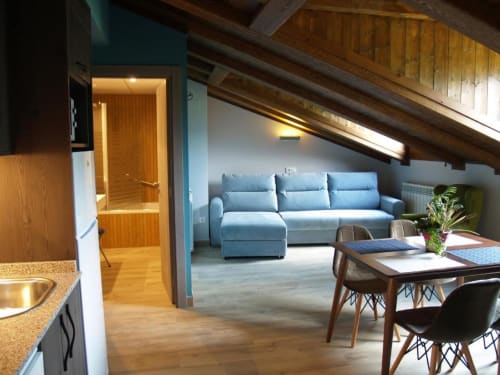 Apartamento de lujo en Hotel Llibrada en Benasque con cocina abierta, comedor y sofá azul en sala de estar