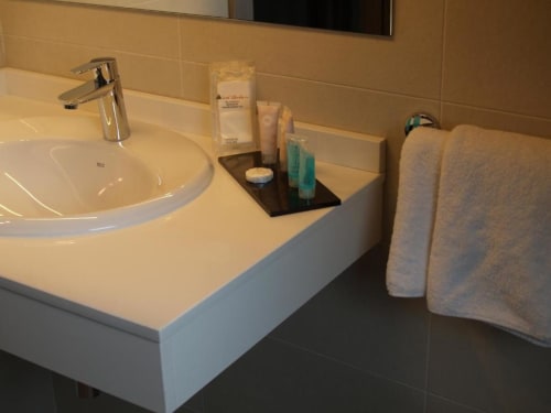 Moderno lavabo de baño con grifo cromado, artículos de tocador y toallero en el apartamento Hotel Llibrada de Benasque