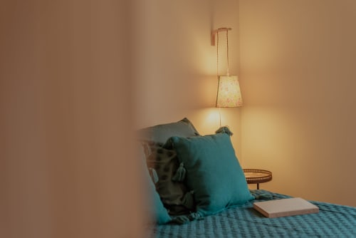 Chambre cosy de Vila Cabanes 46 avec coussins bleu-vert, lampe suspendue et livre sur le lit