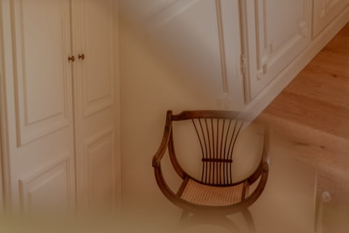 Chaise berçante en bois avec assise tressée dans le couloir de la Vila Cabanes 46, Le Montat