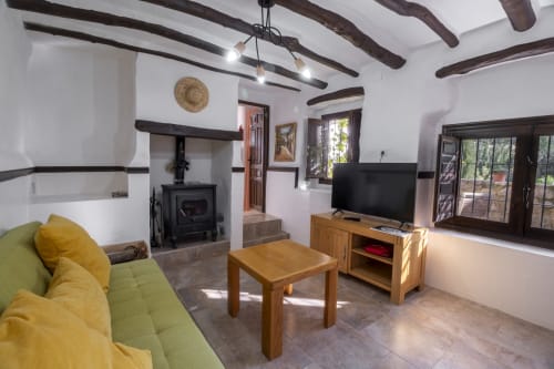 Luminosa sala de estar en El Batán Hotel Spa con vigas vistas, muebles de madera, chimenea y vistas al río desde Casita del Río