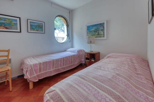 Chambre double aux draps roses à l'appartement Société des Palmiers à Porquerolles, avec hublot et cadre