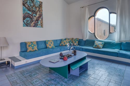 Salon d'appartement moderne avec sièges bleus, table ronde et grande baie vitrée donnant sur le port de Porquerolles.