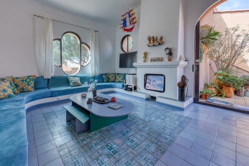 Élégant salon avec canapé bleu-vert, carrelage géométrique et vue sur la mer à l'appartement Société des Palmiers à Porquerolles
