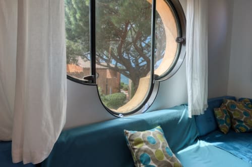 Coin salon bleu avec hublots vue sur la Méditerranée et olivier à l'hôtel-appartement de Porquerolles