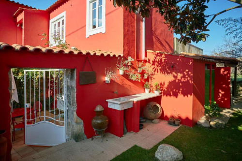 Pátio ao ar livre vermelho vibrante na SOTAM Country House em Góis, com bancos e arquitetura portuguesa tradicional