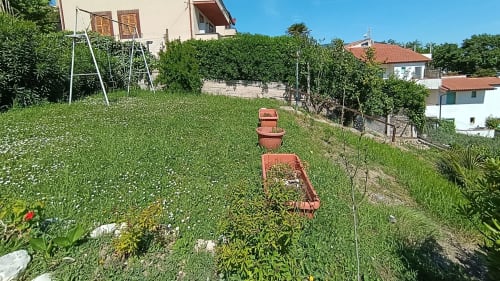 Lush garden view at Casa Bertila in Ancona with terracotta planters and vegetable beds