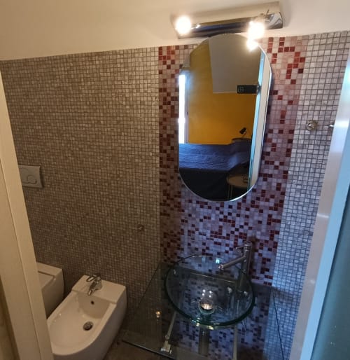 Modern bathroom in Casa Bertila apartment at Immobiliare Marcelli, Ancona, with mosaic tiling, sink, mirror, and shower