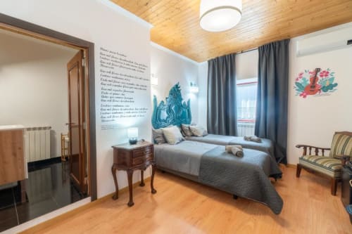 Quarto da SOTAM Country House em Góis com cama, teto de madeira e obra de arte com vista para o jardim