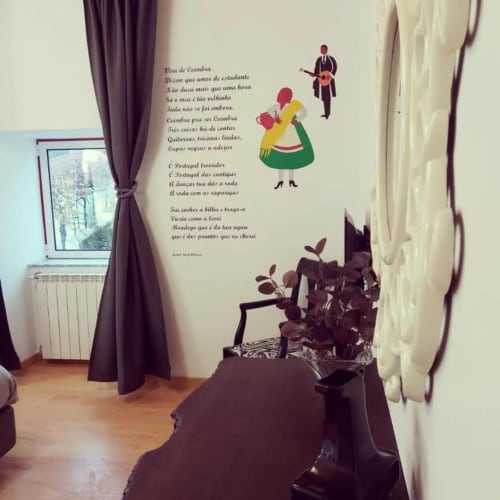 Parede de quarto suíte com arte decorativa apresentando letras de músicas portuguesas e personagens do folclore tradicional na Country House SOTAM, Góis