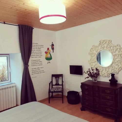 Quarto de suite da SOTAM Country House em Góis com teto de madeira, espelho decorativo, móveis escuros e vista para o jardim