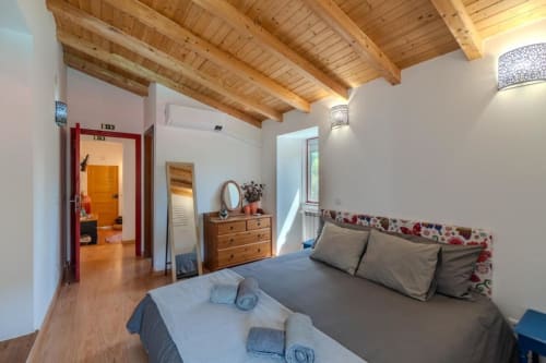 Suite moderna na SOTAM Country House em Góis com vigas de madeira aparente, vista para o jardim e mobiliário em madeira