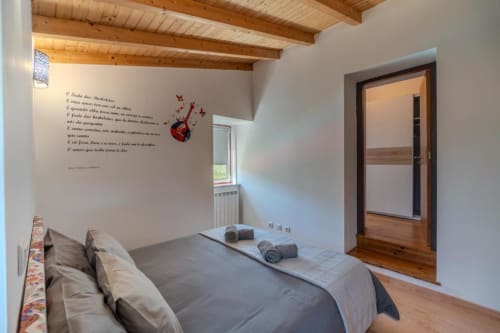 Quarto moderno da SOTAM Country House com vigas de madeira, janela com vista para o jardim e arte inspiradora na parede em Góis